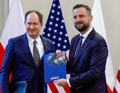 Northrop-Grumman-in-Poland-News two males holding a document in front of flags