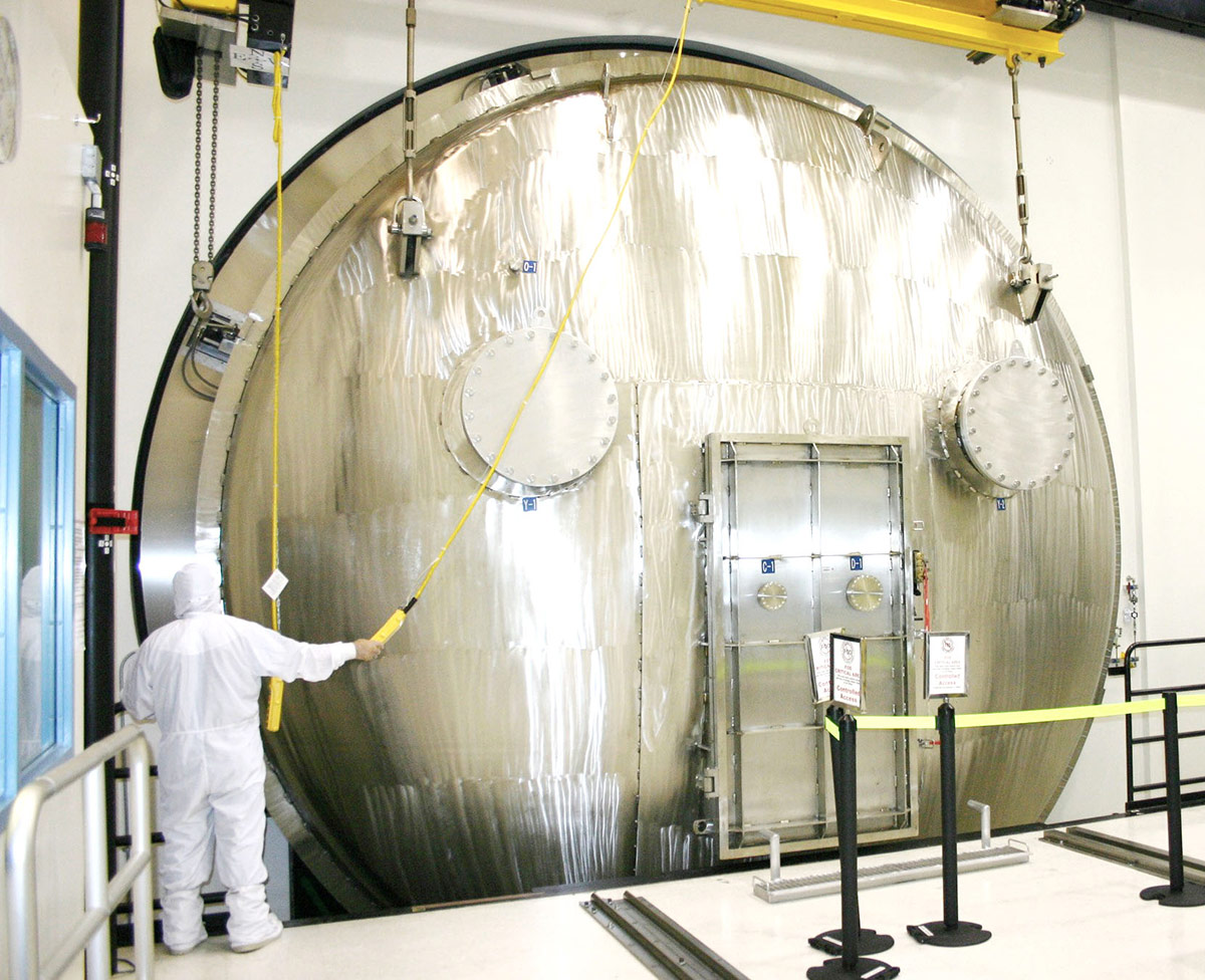 Man in clean suit in front of closed test chamber door
