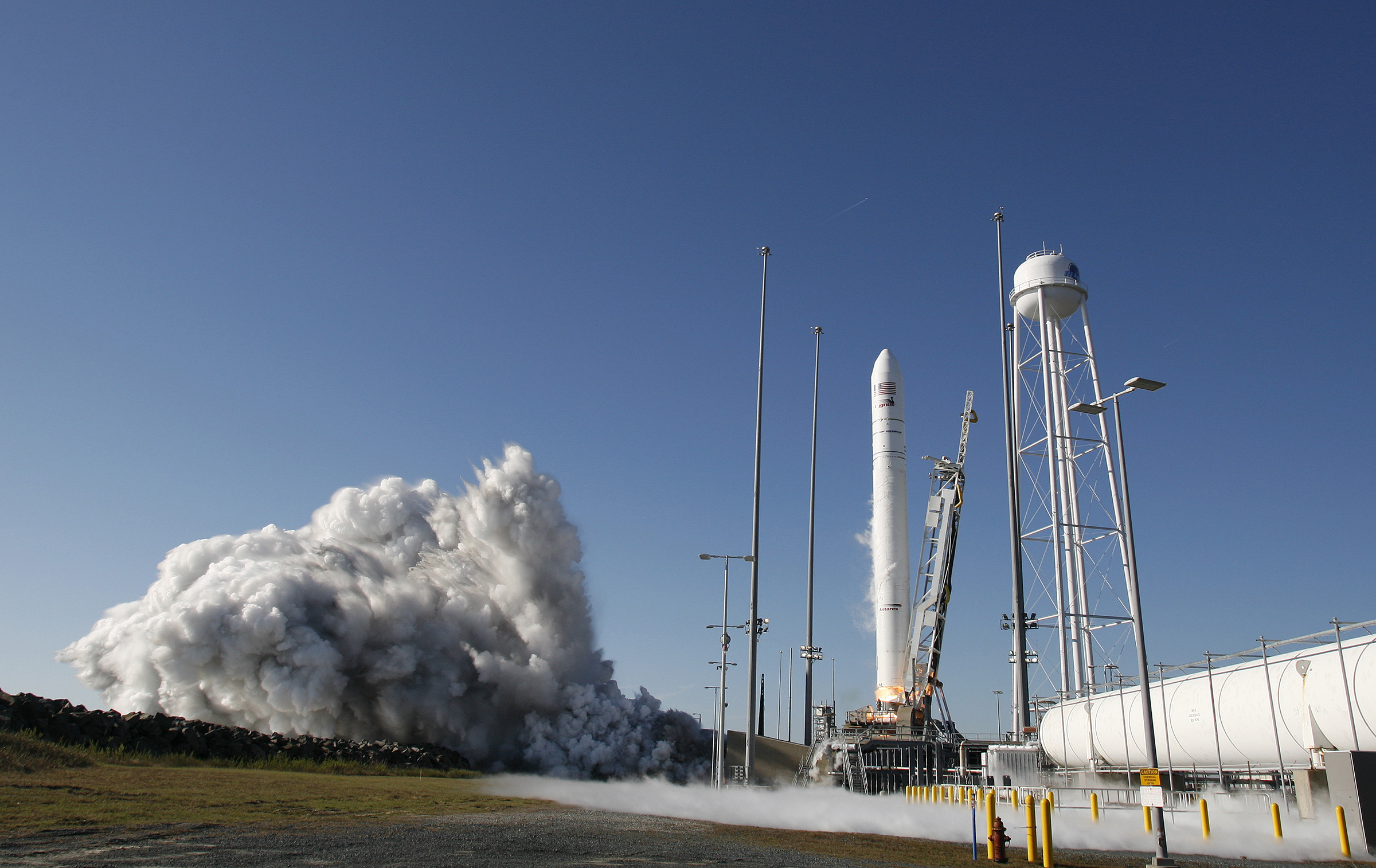 A rocket beginning to liftoff from launch pad in front of a blue sky