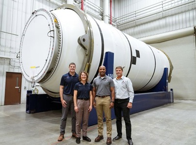 Northrop Grumman Delivers Rocket Booster Segments for NASA’s Artemis II Mission four people standing in front of rocket