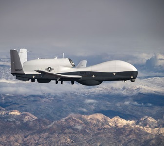 photo of military triton aircraft in flight above mountains.