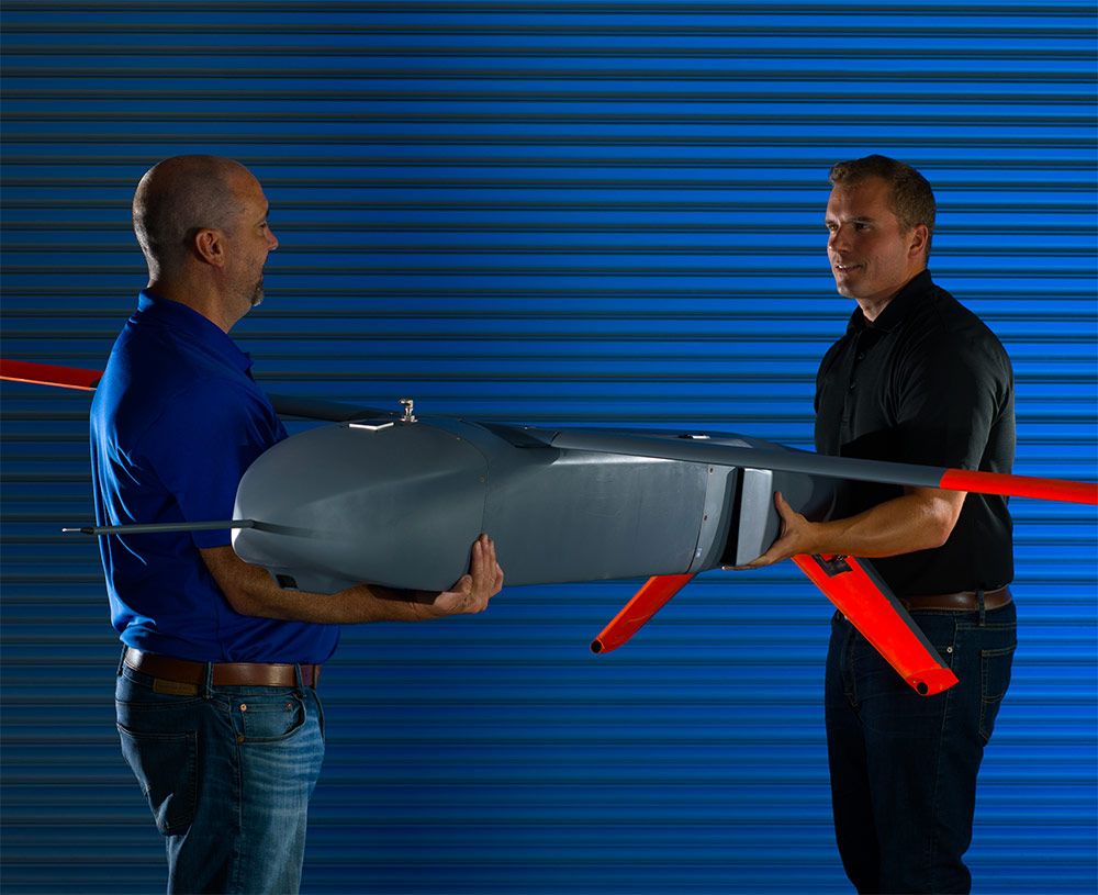 two men holding a uncrewed aircraft system