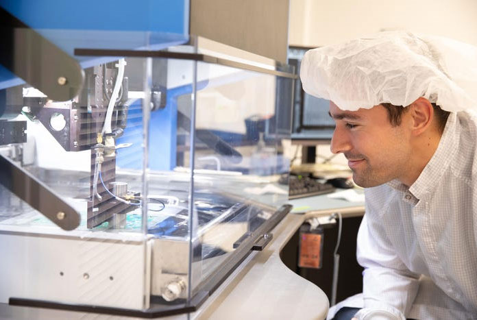 man in lab suit examining equipment