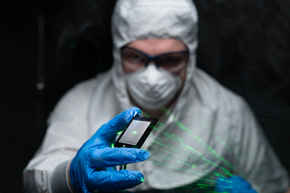 man in cleanroom suit with laser in hand