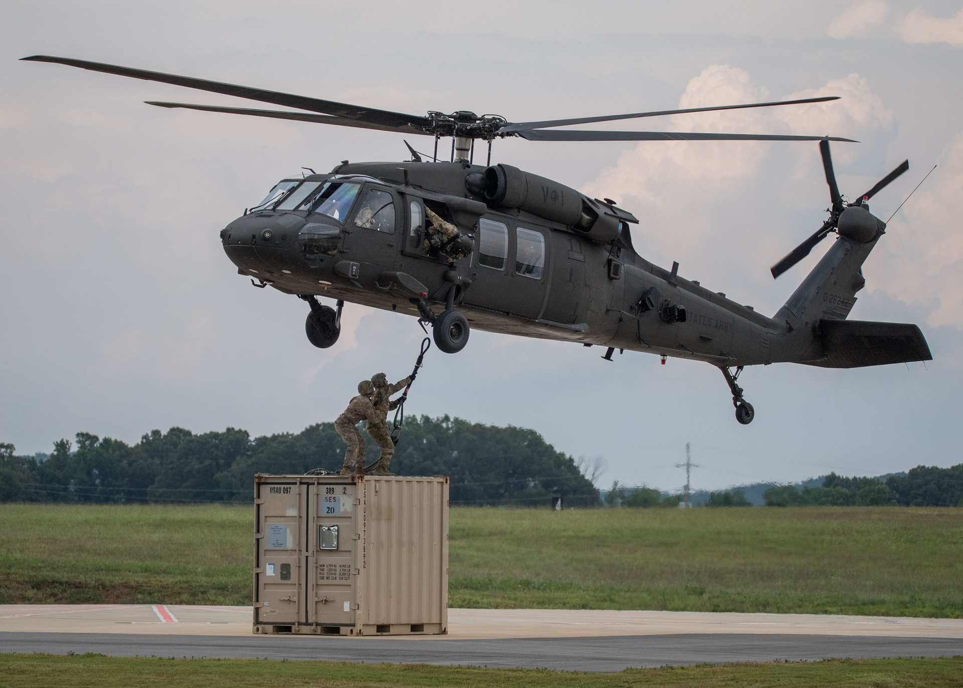 soldiers hoisting equipment to military helicopter