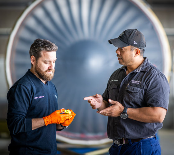 Photo of two men talking and looking at object