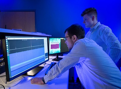 Artificial-Intelligence-and-Machine-Learning-cyber-capture two men are standing, looking at computer screens
