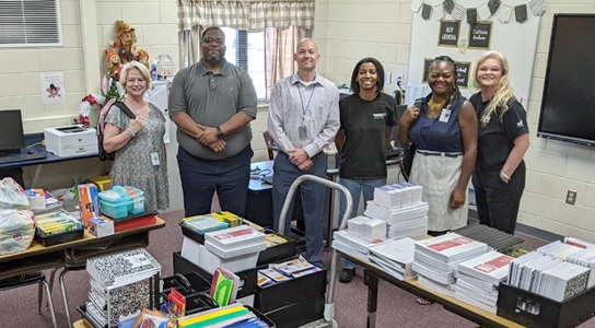 Class Act: Employee Resource Group Helps Students Go Back to School several people lined up in a classroom filled with donations