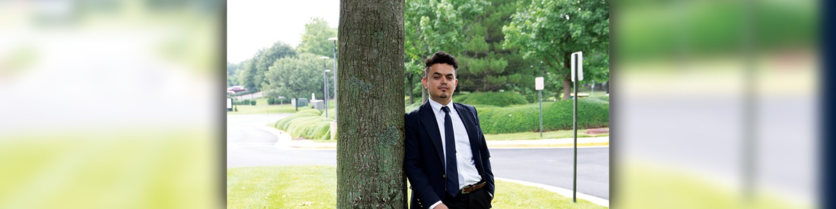 man in suit leaning against a tree