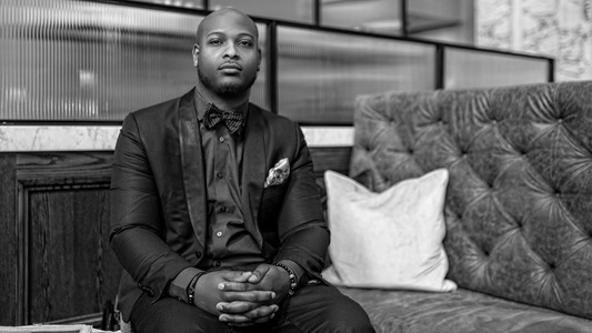 Black man wearing suit sitting on couch