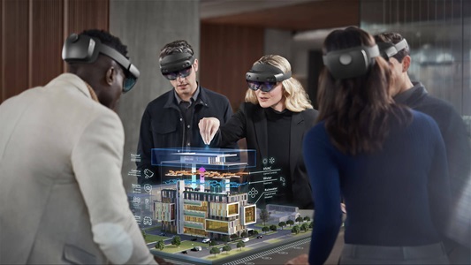 HoloLens-group a group of people wearing HoloLens VR headsets stand around a digital image