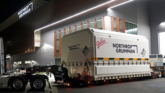 JPSS-2 leaving Northrop Grumman’s Gilbert, Arizona Satellite Manufacturing Facility 002 slide Tracker trailer driving packaged spacecraft from Northrop Grumman facility