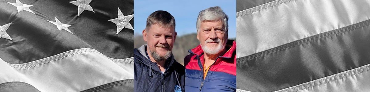2 males smiling with mountain backdrop