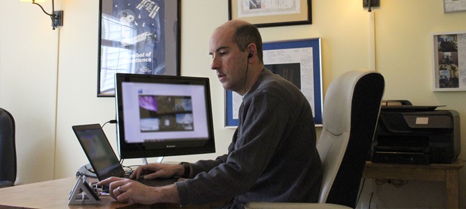 white man working from home in front of several computer monitors