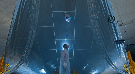Scientist in lab coat looking up at the James Webb Space Telescope (JWST)