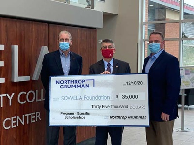 three men hold an oversize check demonstrating financial support