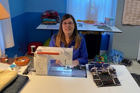 woman with glasses on a sewing machine in her home