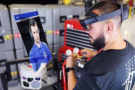 The End Game (feature tile) a man wears a XR headset to watch a video to work on machinery (image sized for a feature tile)