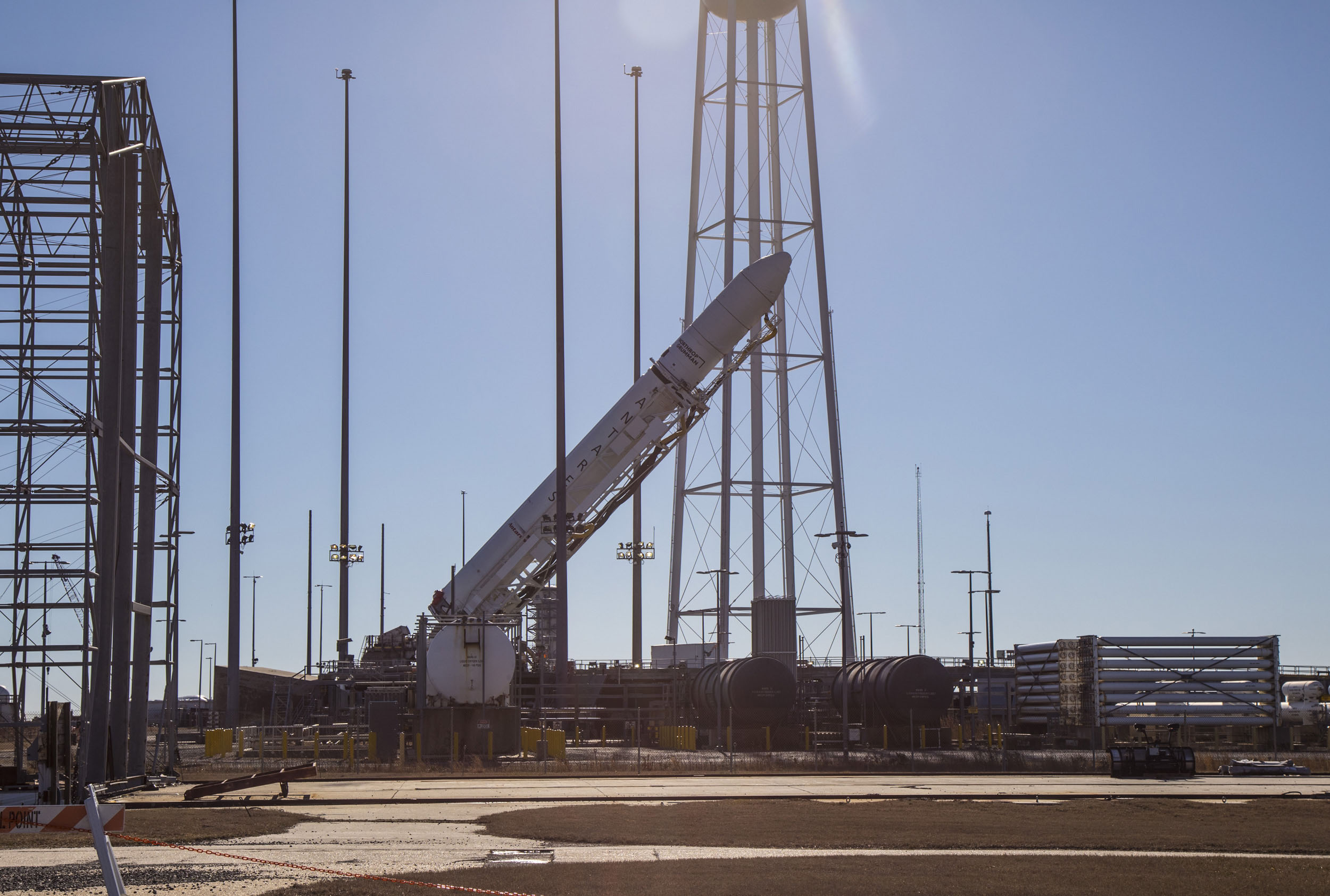 NG_15_Antares_Rocket A rocket tilted sideways on launch pad as it is being placed in launch postion in front of a blue sky