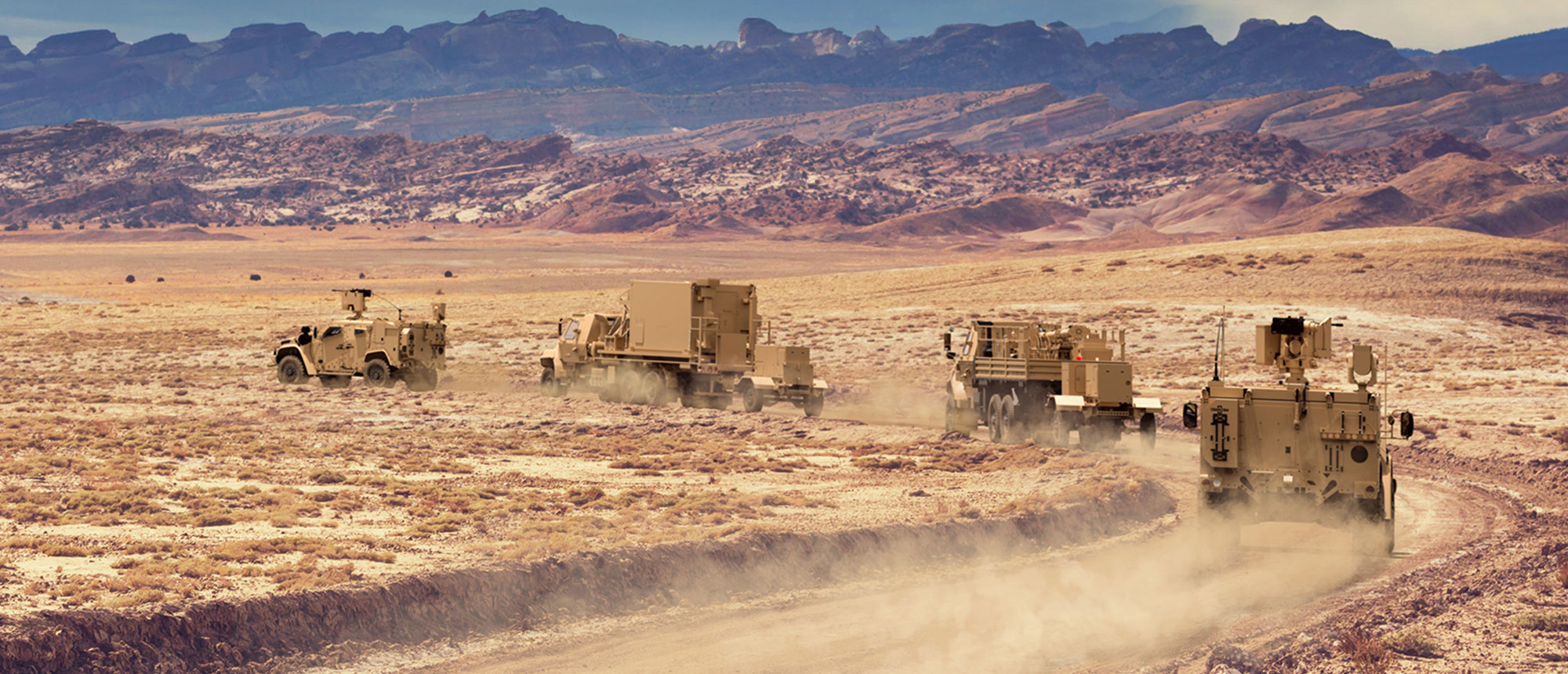 Connecting Forces Across All Domains army truck convoy in mountainous desert