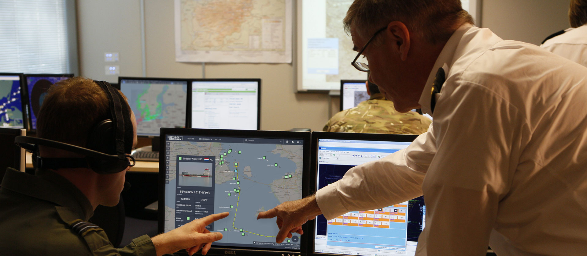 Two men looking and pointing at laptop display in office setting. 