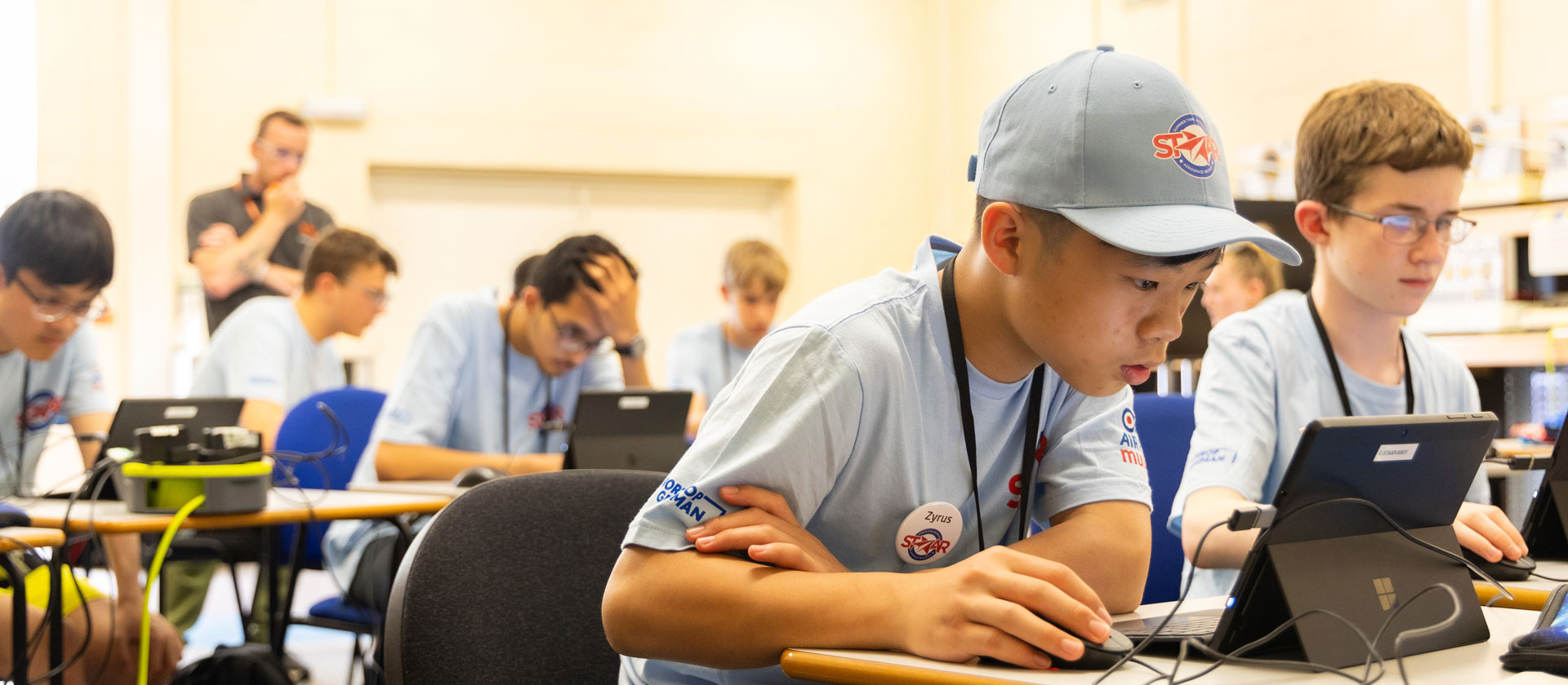Student in sitting at desk in classroom wearing a STAAR ballcap