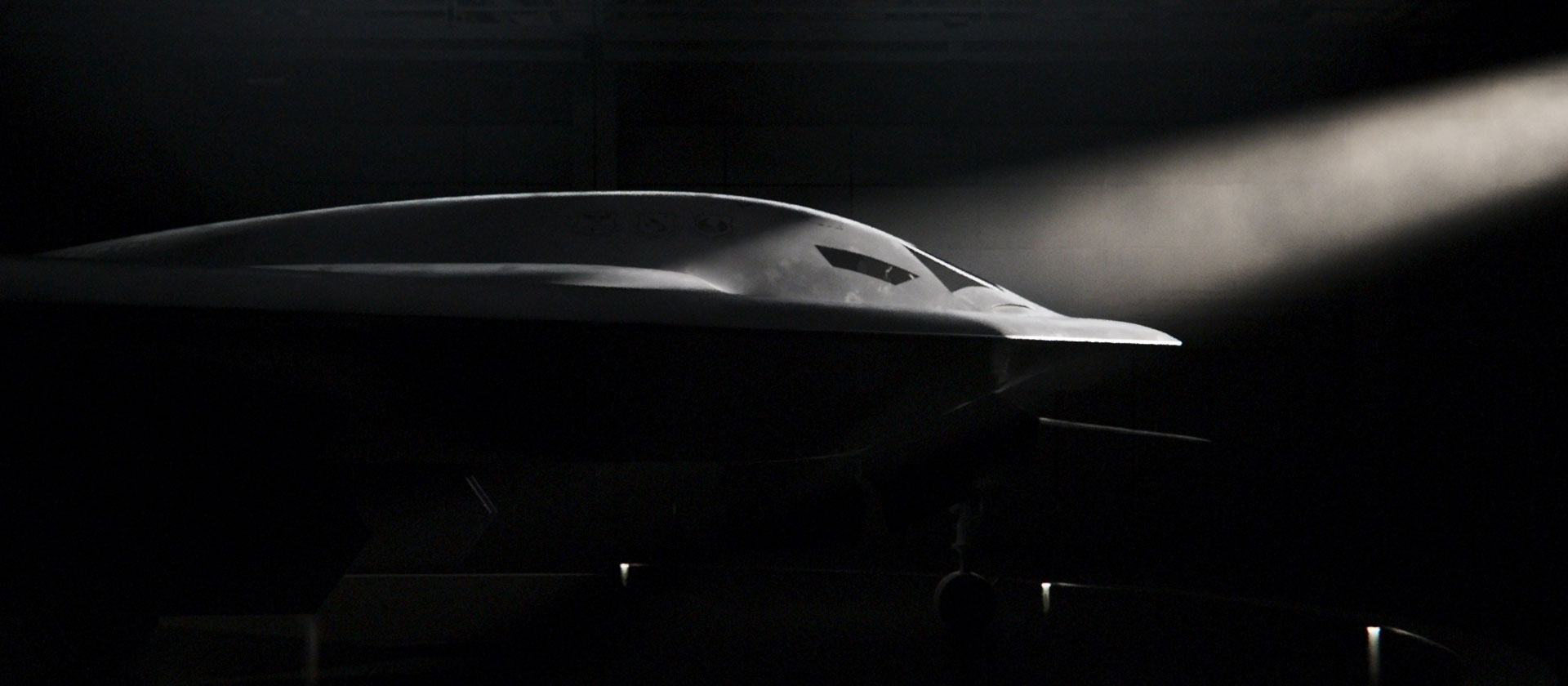 photo of profile of B-21 in hanger with spotlight