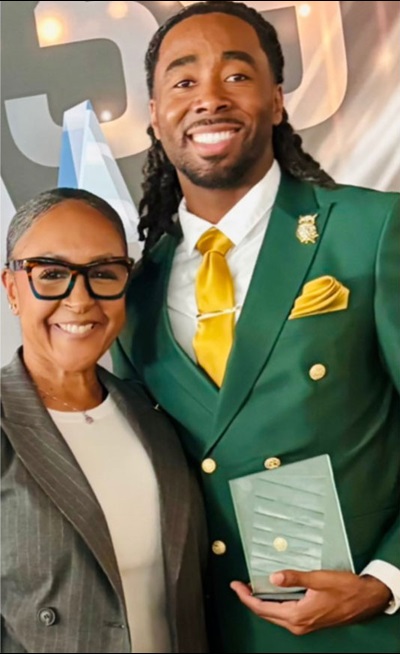 Two people smiling, one is holding an award