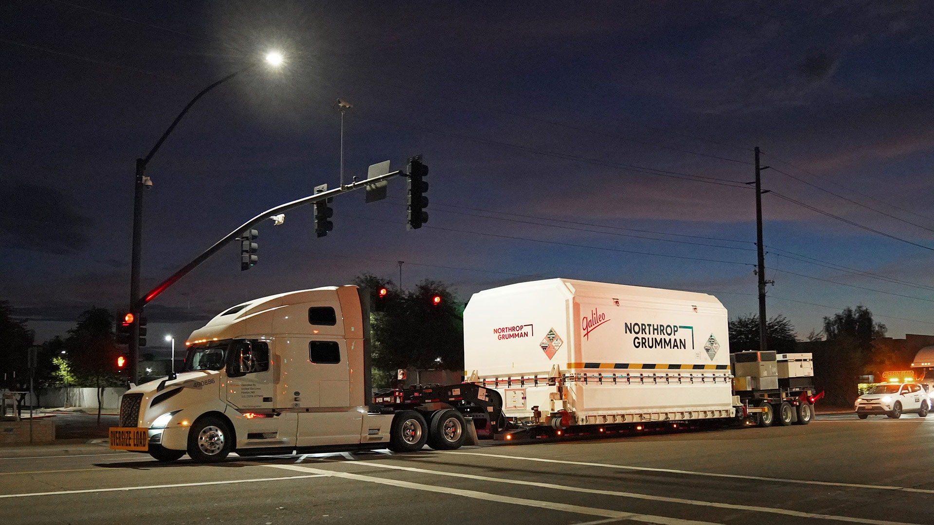 JPSS-2 leaving Northrop Grumman’s Gilbert, Arizona Satellite Manufacturing Facility 003 slide Tracker trailer carrying packaged spacecraft
