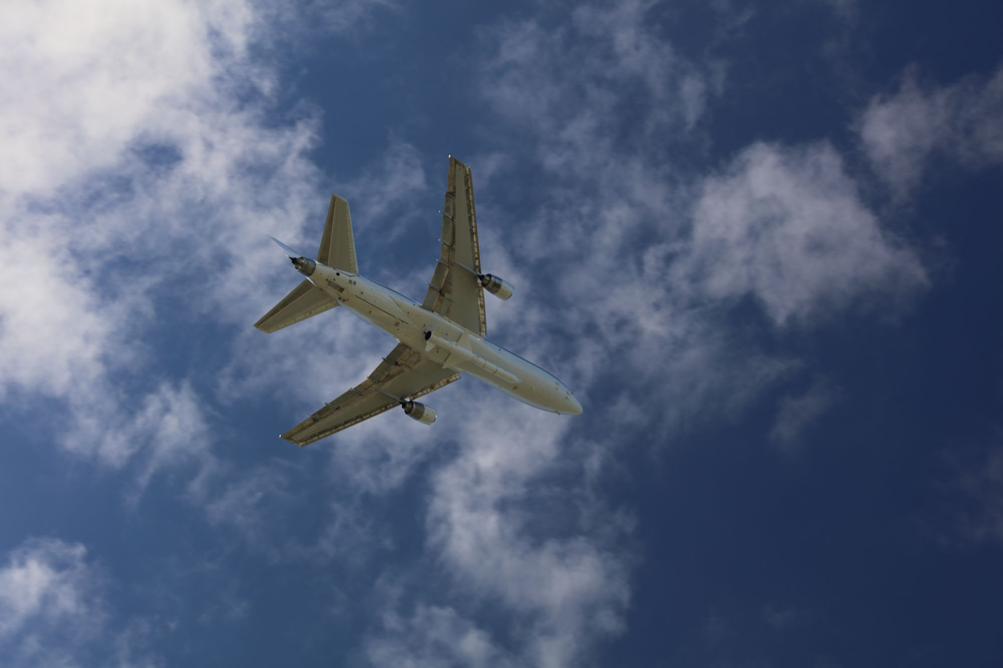 Pegasus_L1011 in flight Resize View from ground of the belly of an airplane carrying a rocket in a blue sky with light clouds